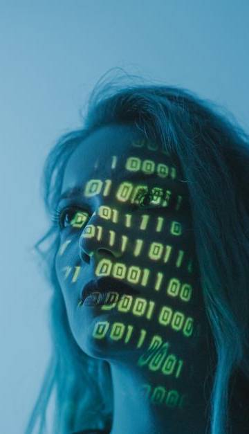 A woman with binary code lights projected on her face, symbolizing technology.