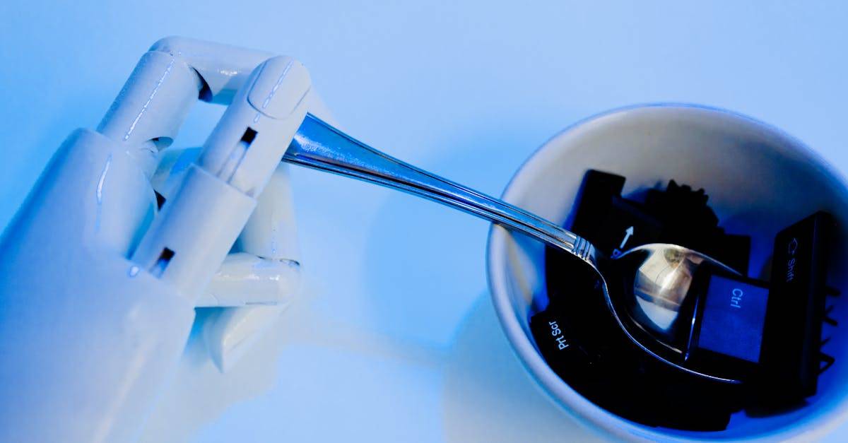 A robotic hand holding a spoon above a bowl with keyboard keys, showcasing technology themes.