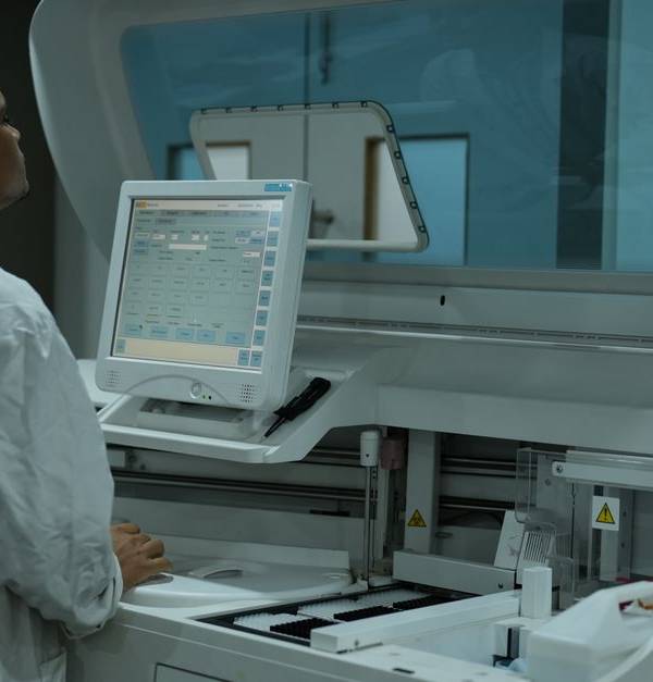 A lab technician operates a clinical analyzer in a modern laboratory setting.