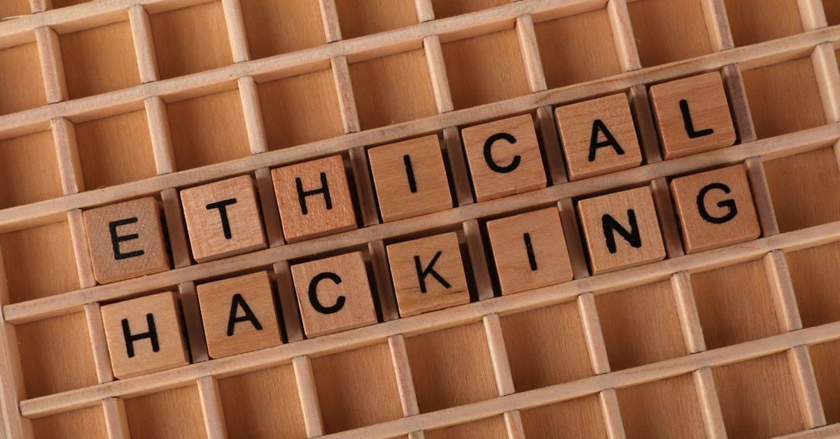 Wooden letter blocks spelling 'Ethical Hacking' on a grid background, symbolizing cybersecurity.