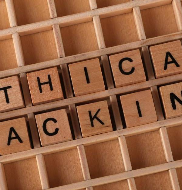 Wooden letter blocks spelling 'Ethical Hacking' on a grid background, symbolizing cybersecurity.