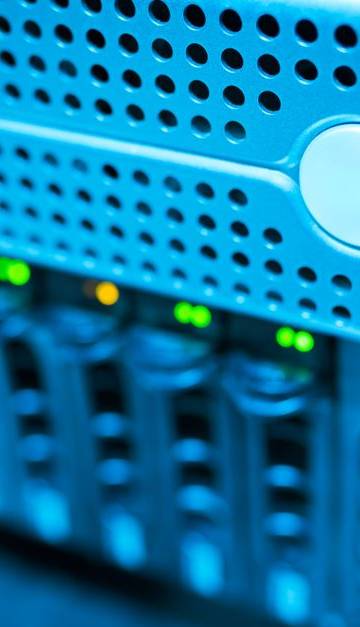 Focused view of a modern data server rack with blinking lights in a blue-lit environment.