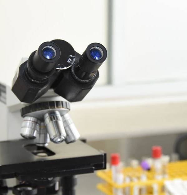 A close-up of a laboratory microscope with test tubes in a scientific research facility.
