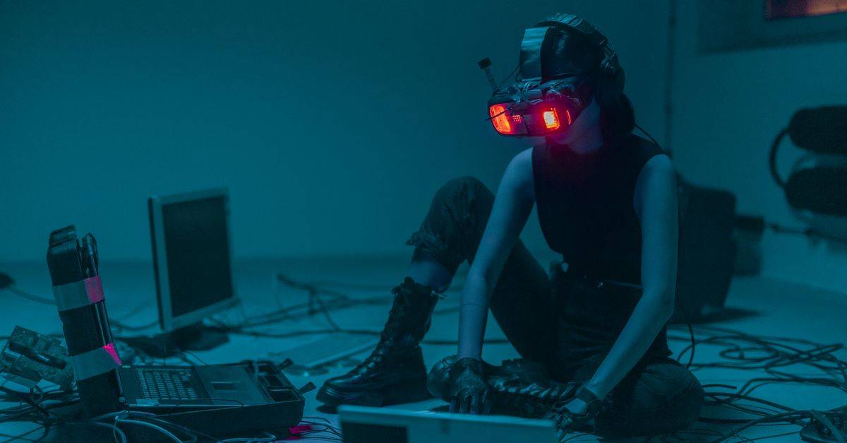 A person in a VR headset hacking in a moody, neon-lit environment.