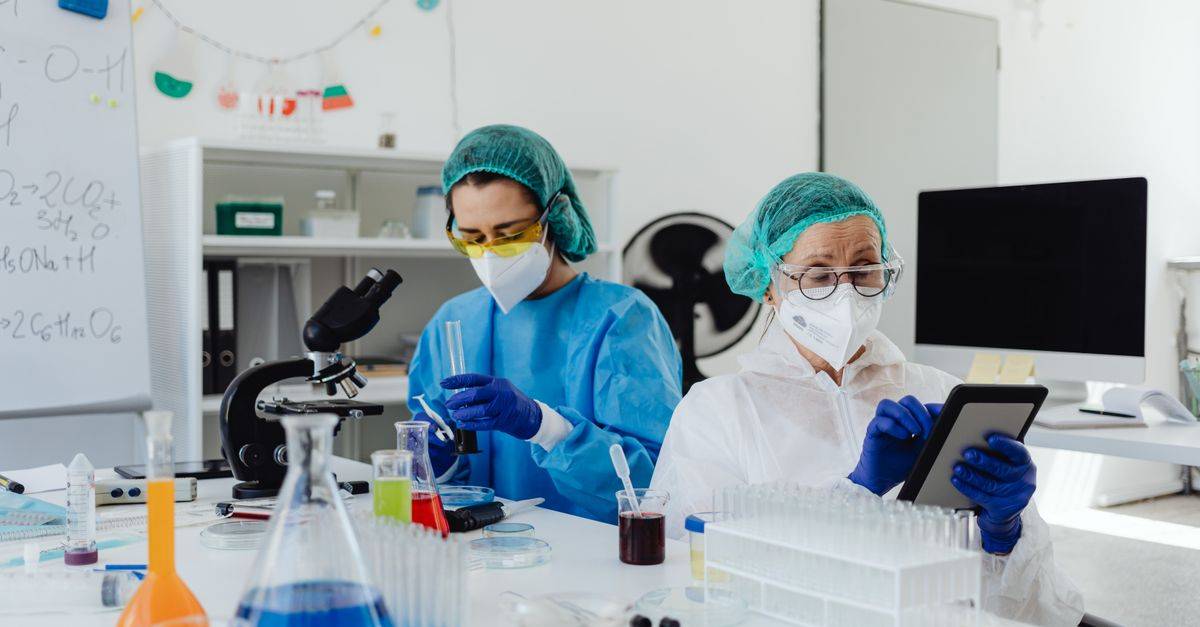 Researchers conducting experiments in a laboratory, using microscopes and digital tablets.