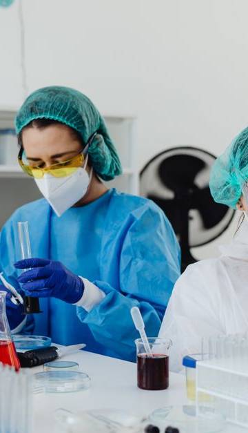 Researchers conducting experiments in a laboratory, using microscopes and digital tablets.