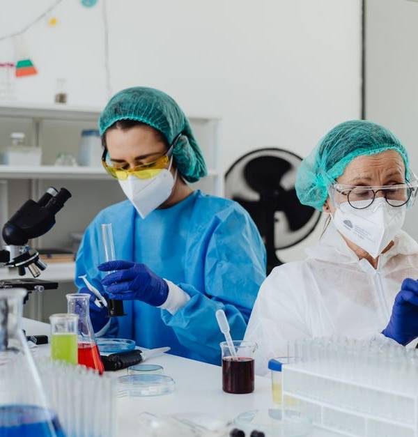 Researchers conducting experiments in a laboratory, using microscopes and digital tablets.