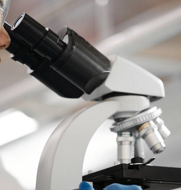Male scientist studies samples under microscope in modern laboratory setting.