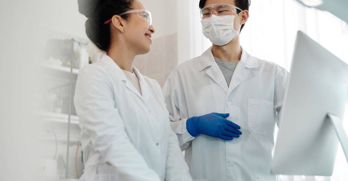 Two scientists wearing safety gear collaborate on a research project in a laboratory setting.