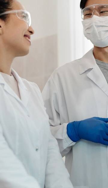 Two scientists wearing safety gear collaborate on a research project in a laboratory setting.