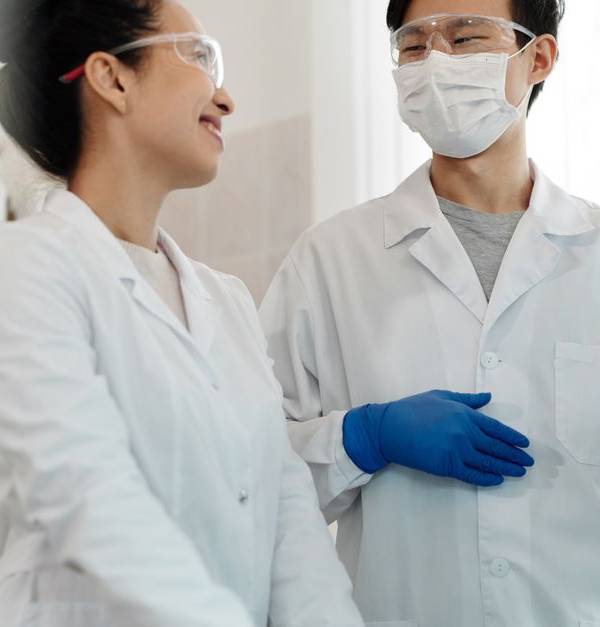 Two scientists wearing safety gear collaborate on a research project in a laboratory setting.