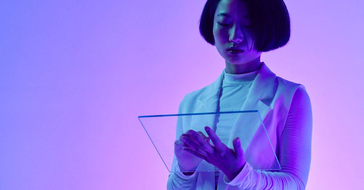 Woman interacts with a transparent digital screen in vibrant studio lighting.