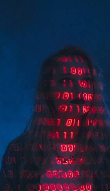 A mysterious silhouette with red binary code projected over the face, set against a dark, moody background.