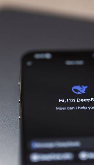 Close-up of a smartphone with AI assistant interface on screen over a laptop.
