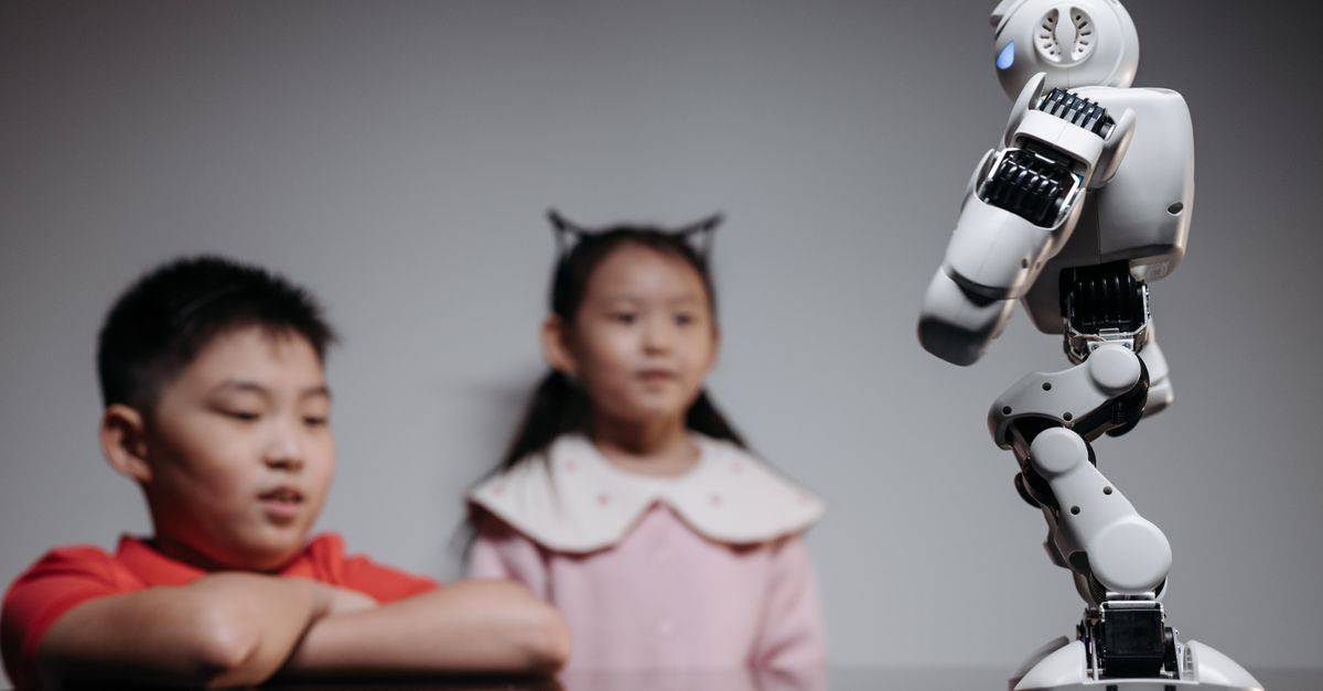Two children watching and interacting with an innovative robot toy indoors.