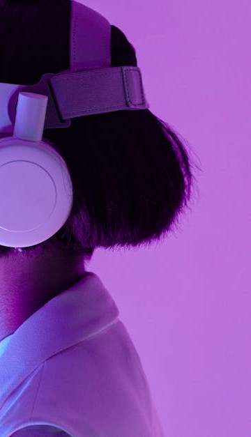 Side view of a woman wearing VR goggles in a purple-lit studio, highlighting modern technology.