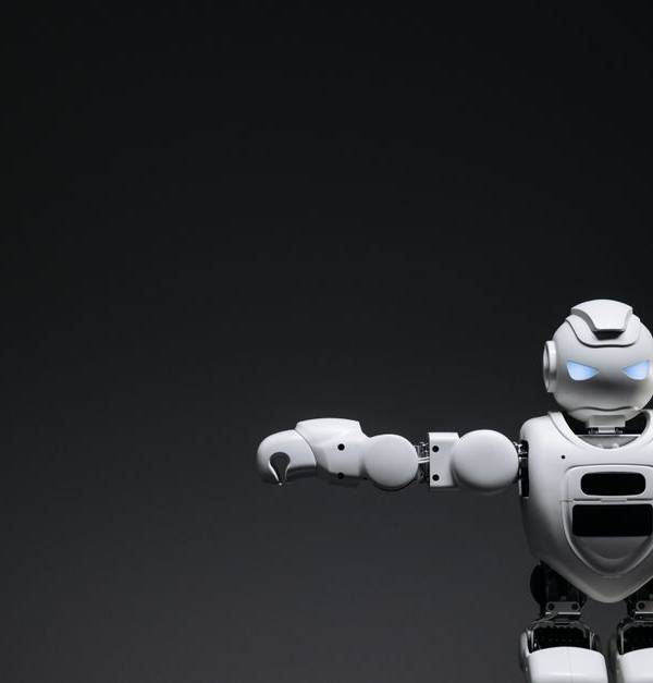Studio shot of a humanoid robot with glowing eyes against a dark background, offering ample copyspace.
