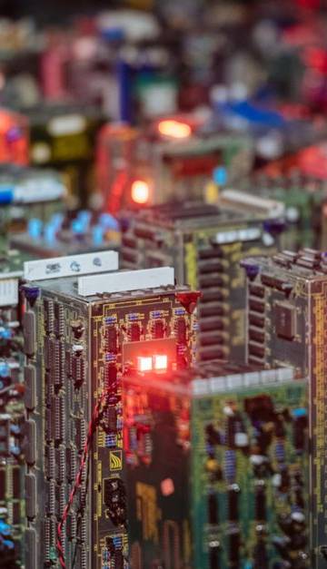 Close-up view of illuminated circuit boards resembling a cityscape, showcasing intricate electronic design.
