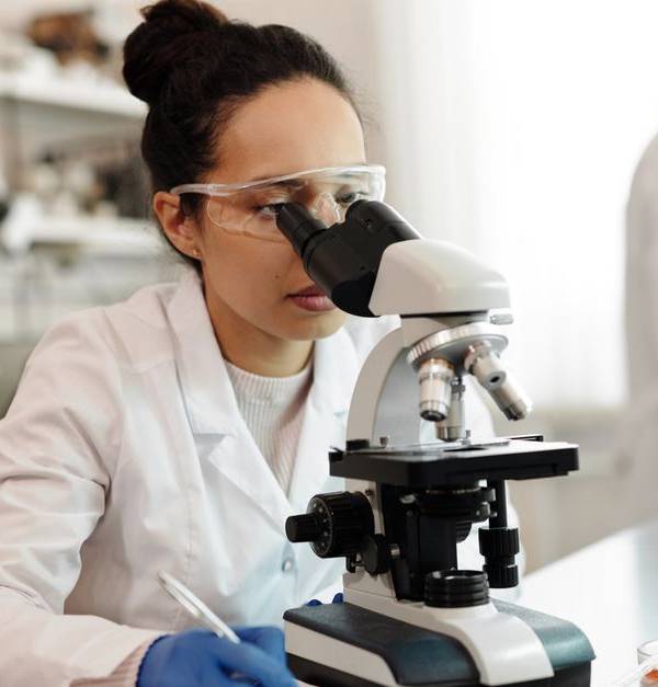 A scientist in a lab coat using a microscope in a modern laboratory setting.