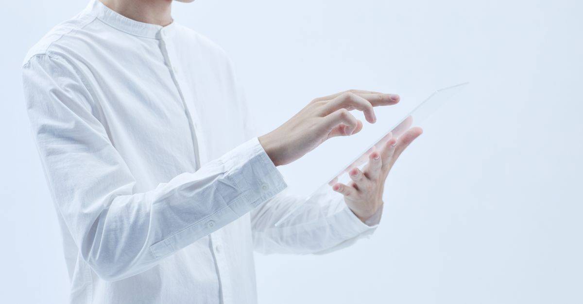 Person interacting with a transparent digital tablet, symbolizing technology and futurism.