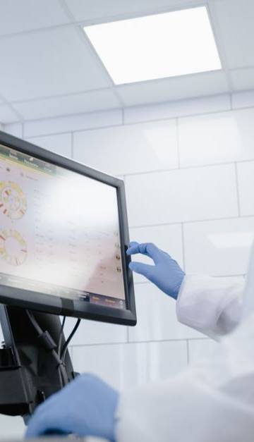 Woman in lab coat using touchscreen monitor in a modern laboratory setting.